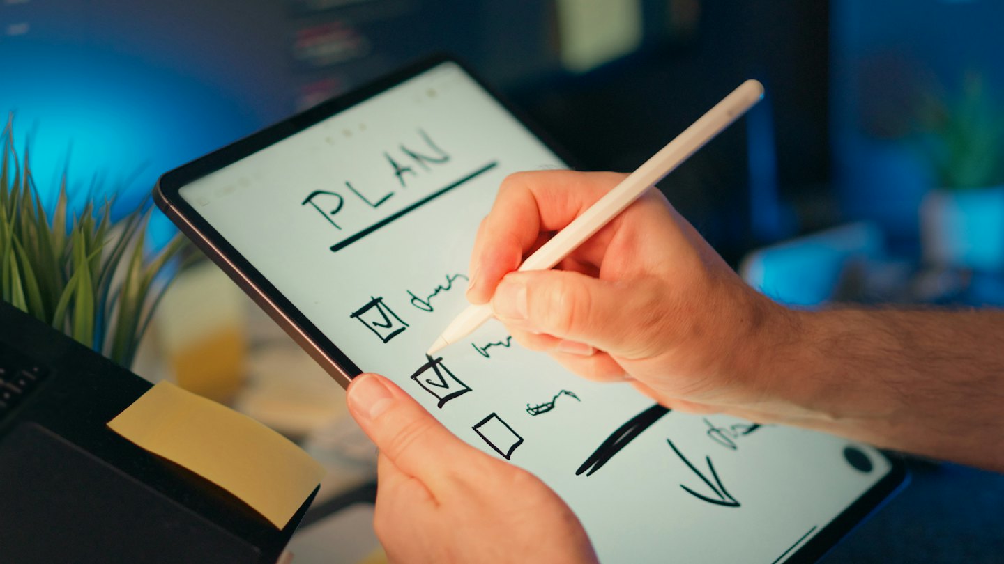 Hände benutzen einen digitalen Stift auf einer Checkliste auf einem Tablet.